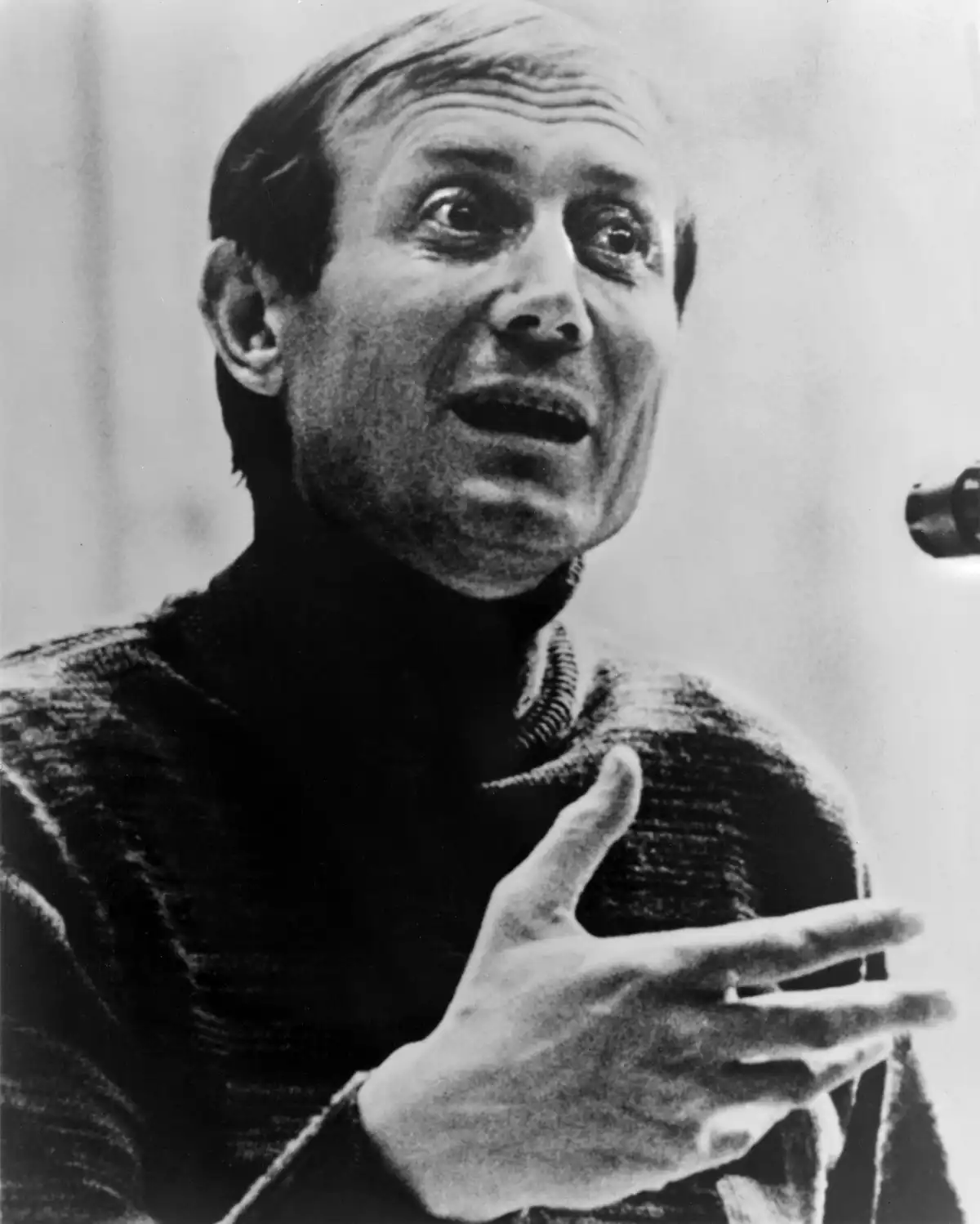 Yevgeny Yevtushenko, retrato de busto, ligeramente hacia la derecha, gesticulando y hablando ante un micrófono.
