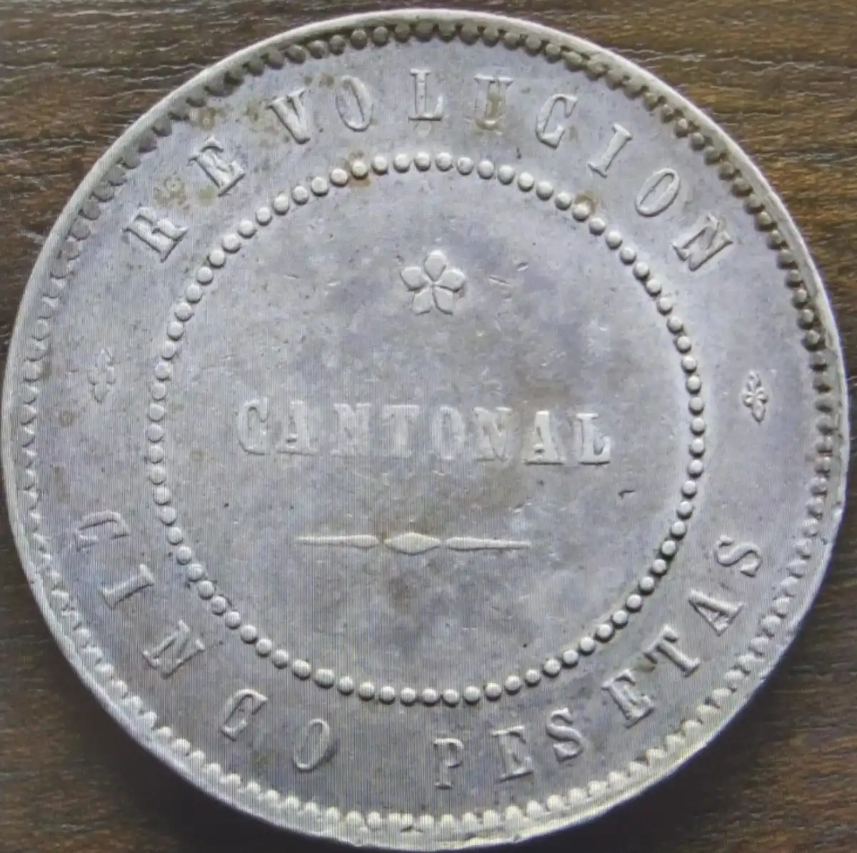 Anverso de la moneda de cinco pesetas acuñada por el Cantón de Cartagena en 1873, con la leyenda «Cartagena sitiada por los centralistas».