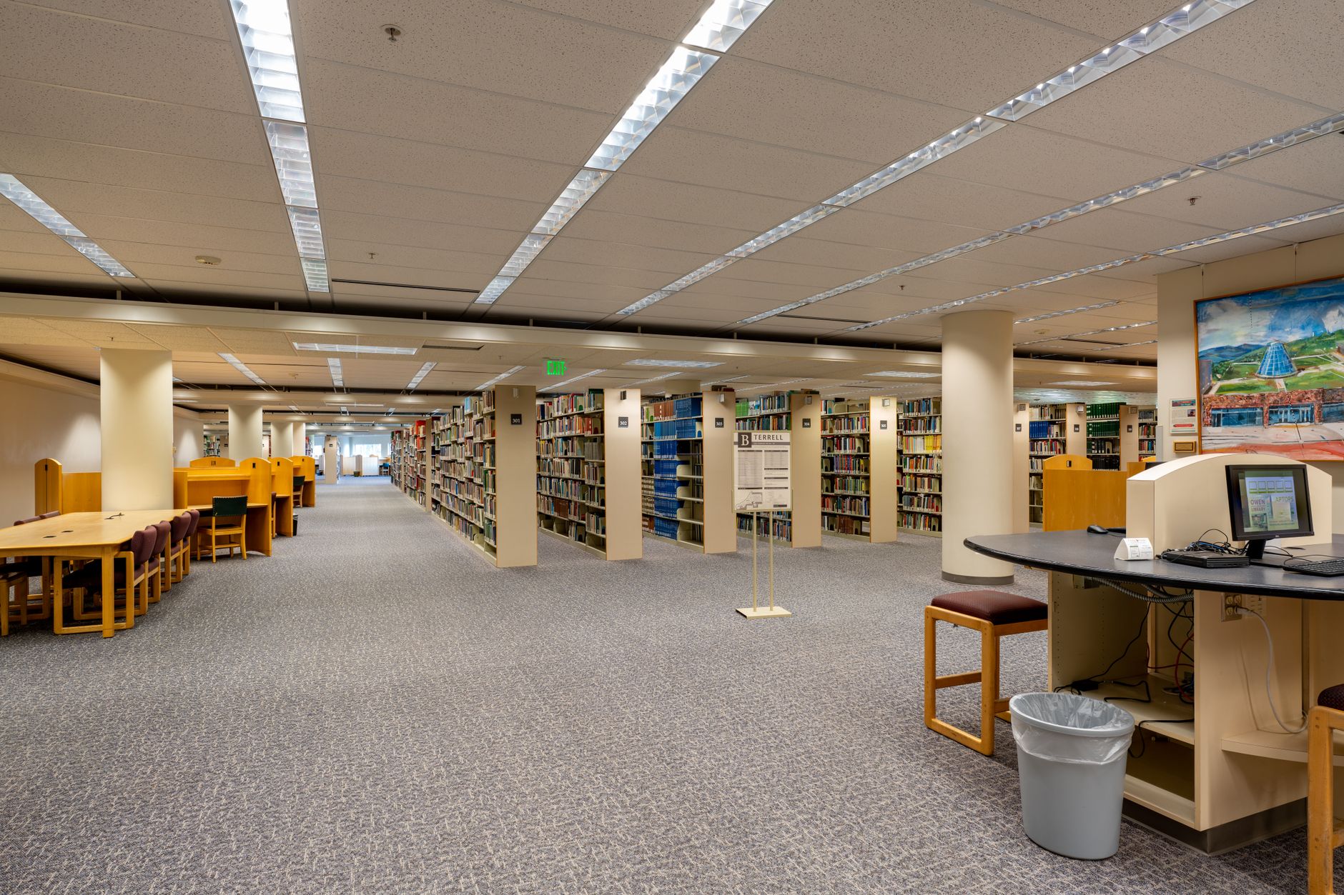 university library with rows of books and students researching at desks with computers and academic materials