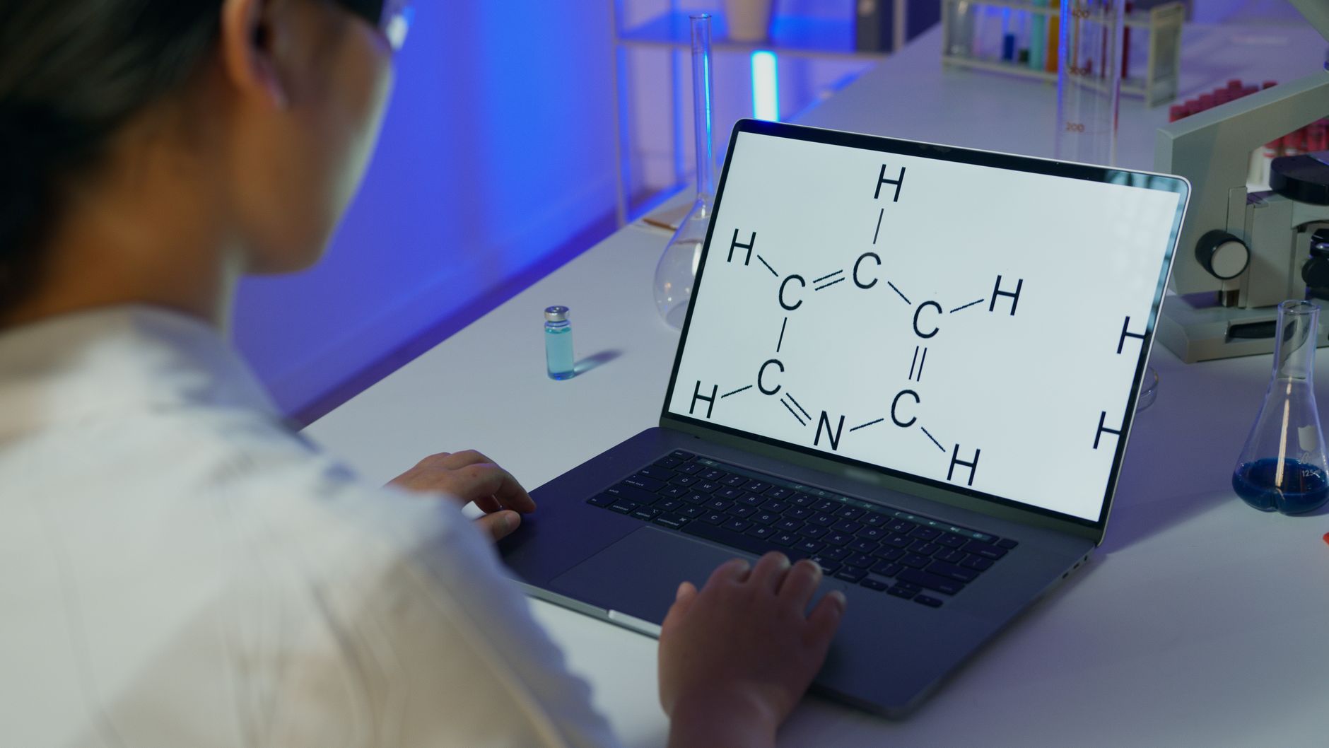 scientist analyzing atomic resolution microscope data on screen dark laboratory blue light