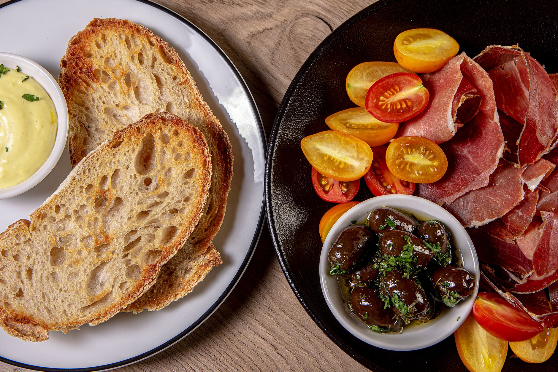artisan cured ham and olive oil bottle on rustic wooden table golden mediterranean light