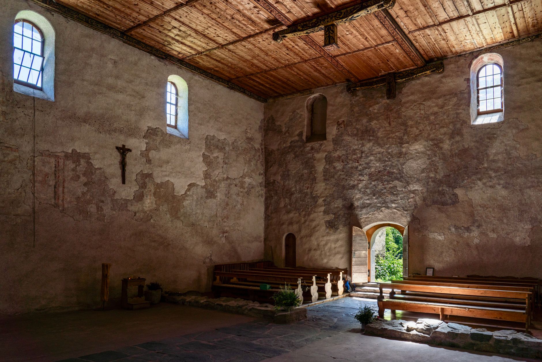 elderly woman opening ancient wooden church door soft light
