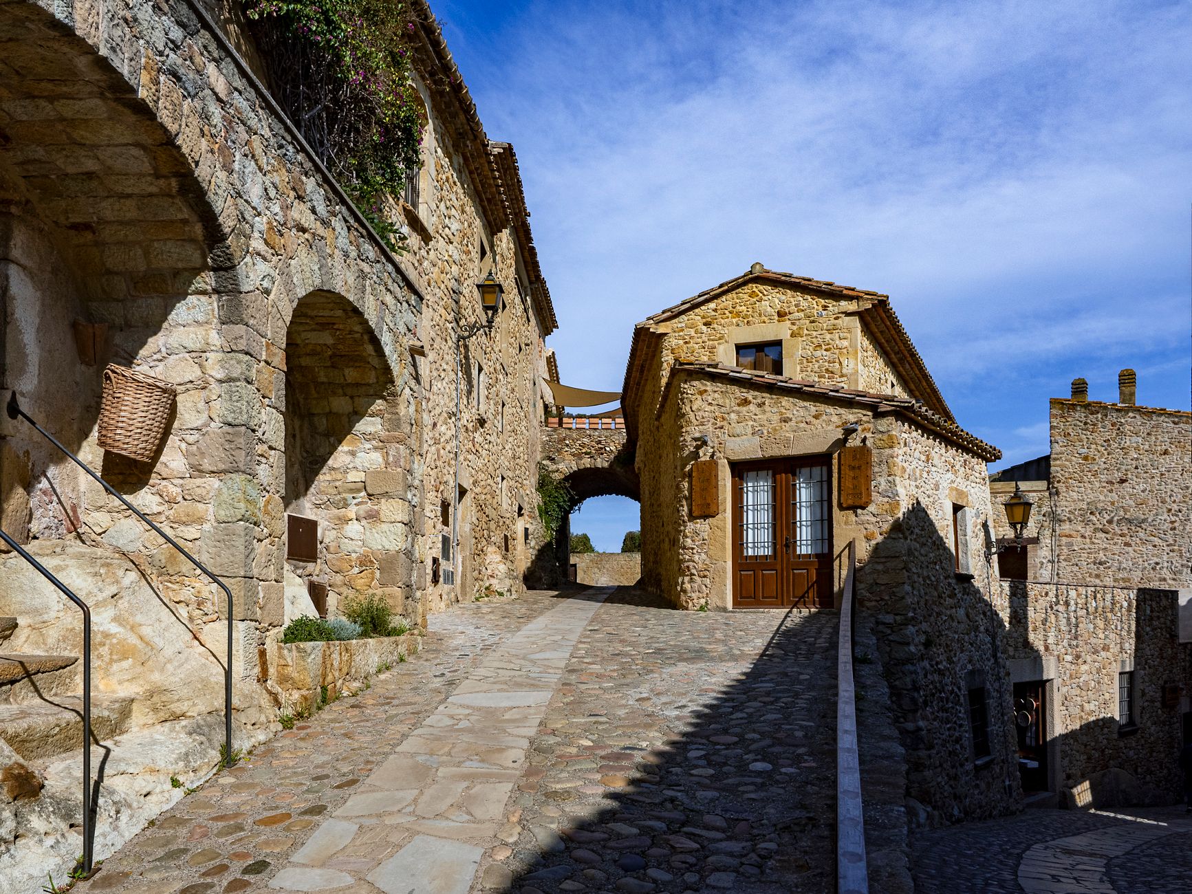 rustic Castilian village square at golden hour, weathered stone houses, secretive old-world atmosphere