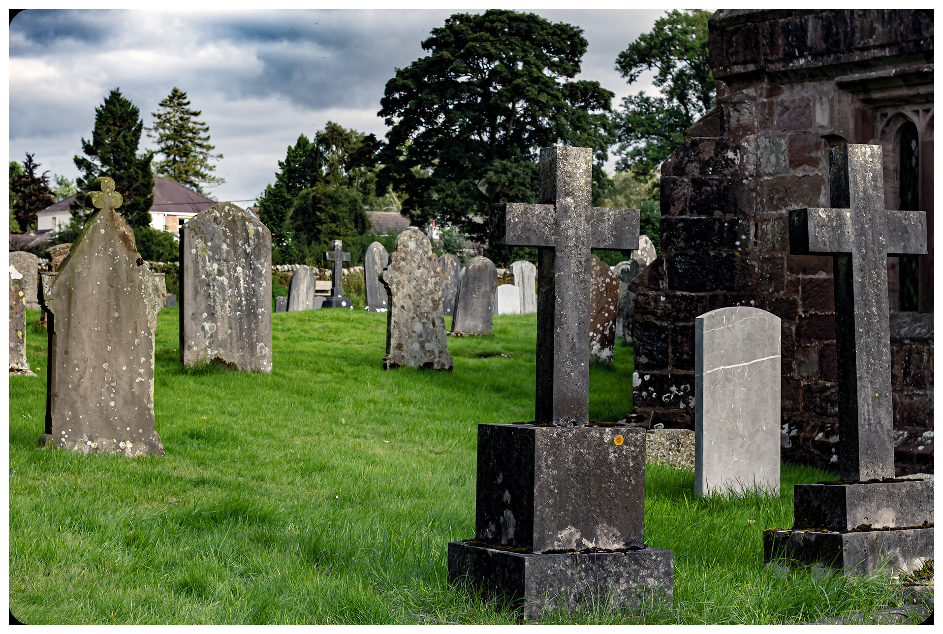 ancient stone cemetery with overgrown grass and wooden cross markers, misty Galician landscape, golden hour light creating long shadows