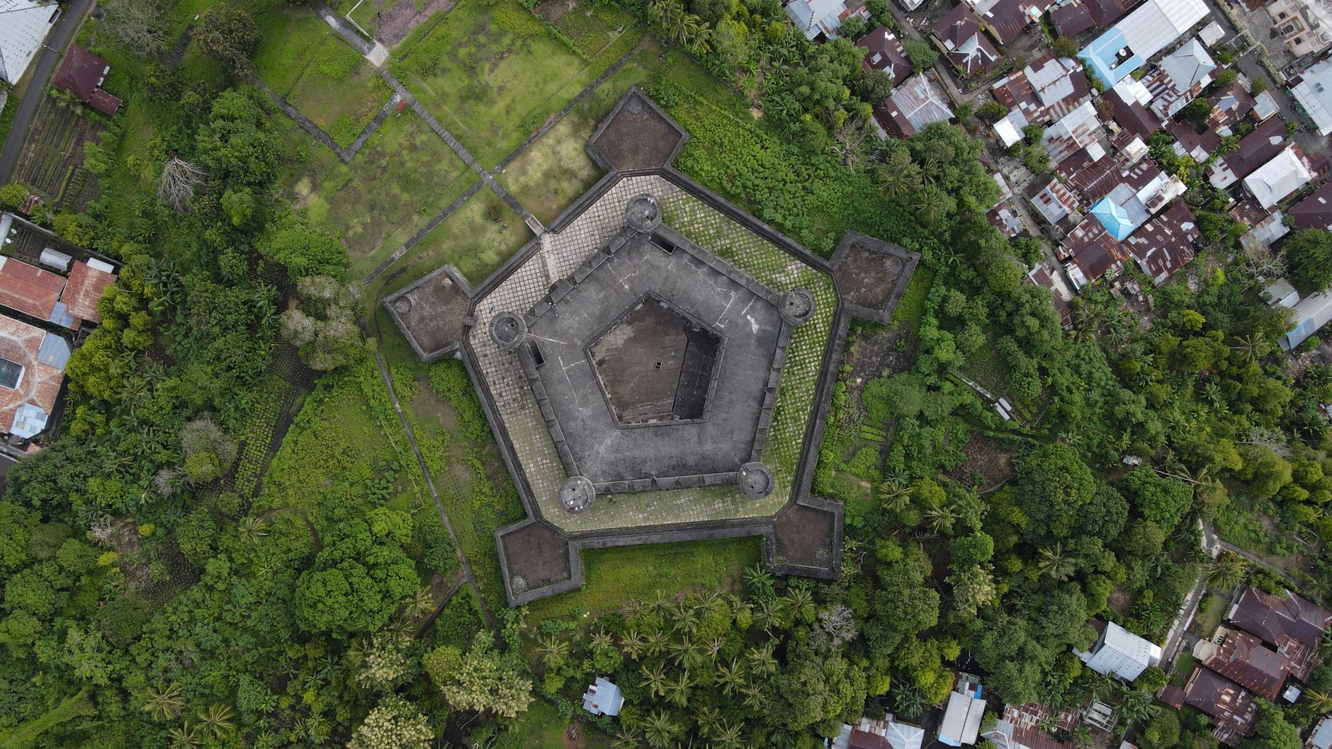 aerial view of pentagonal copper age fortress with concentric stone walls carved moats solid rock excavation site under bright sunlight